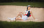 Woman in golf bunker wearing women's golf accessories, golf socks and golf visor