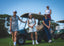 Four women on a golf course with golf carts and clubs.