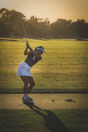 Woman playing golf on a well-maintained course with trees in the background