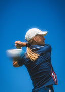 Person playing golf with a clear blue sky background